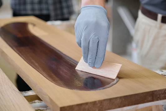 closeup of workers hand covering wooden plank