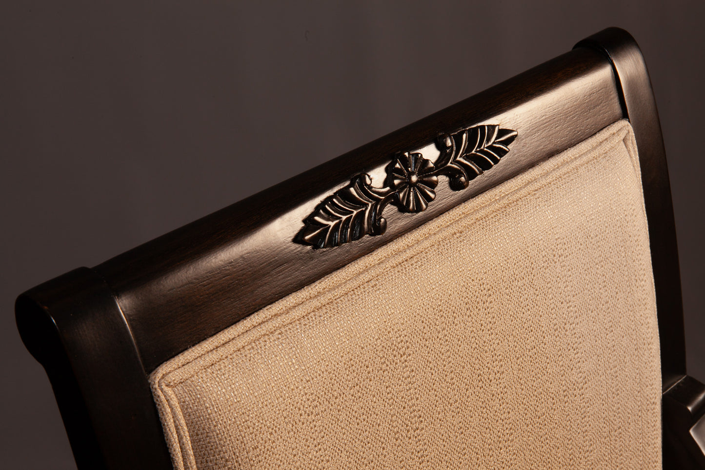 Front view of Empire-style armchair highlighting ornate carvings and cushioned seat.