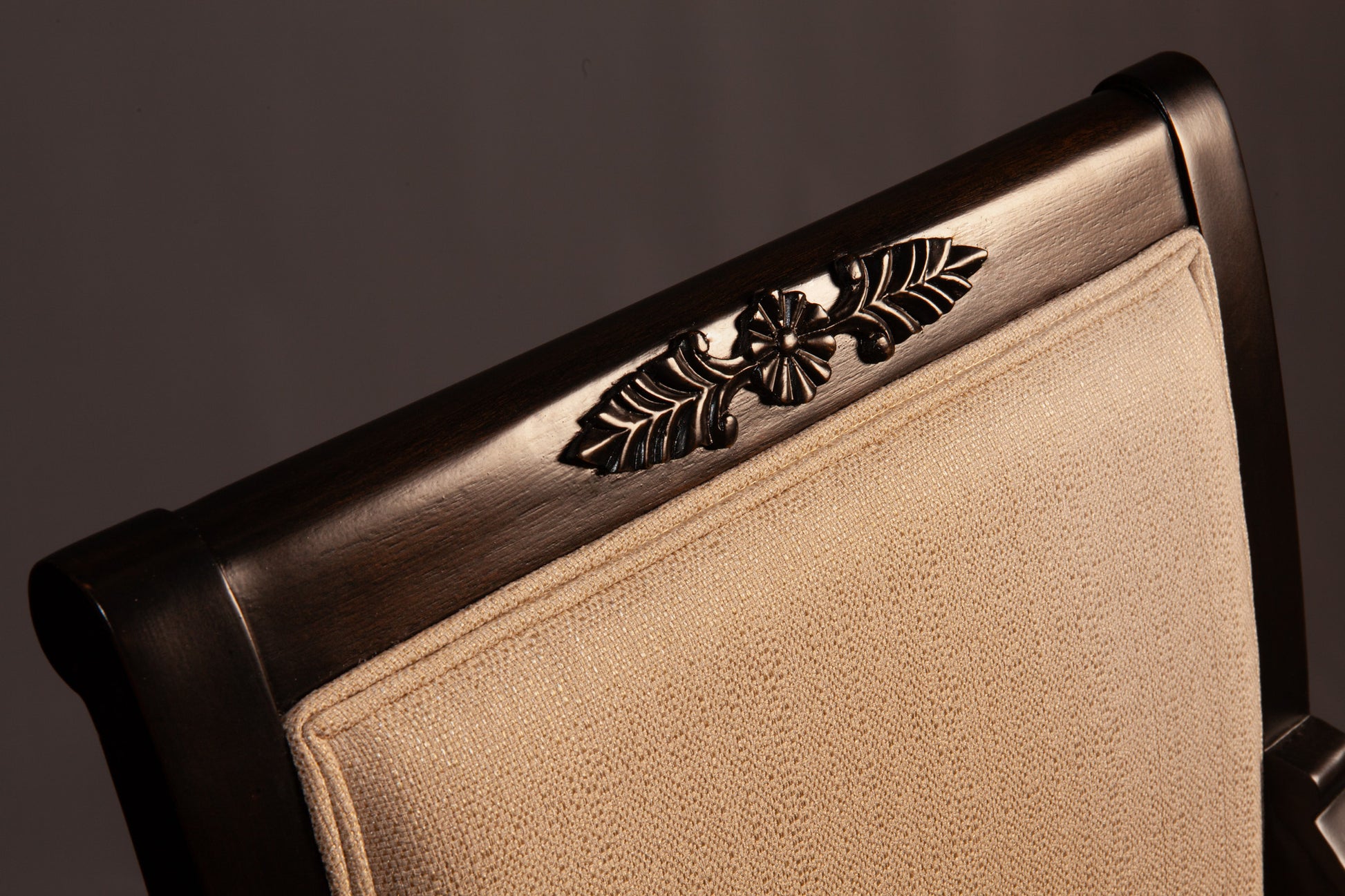Front view of Empire-style armchair highlighting ornate carvings and cushioned seat.
