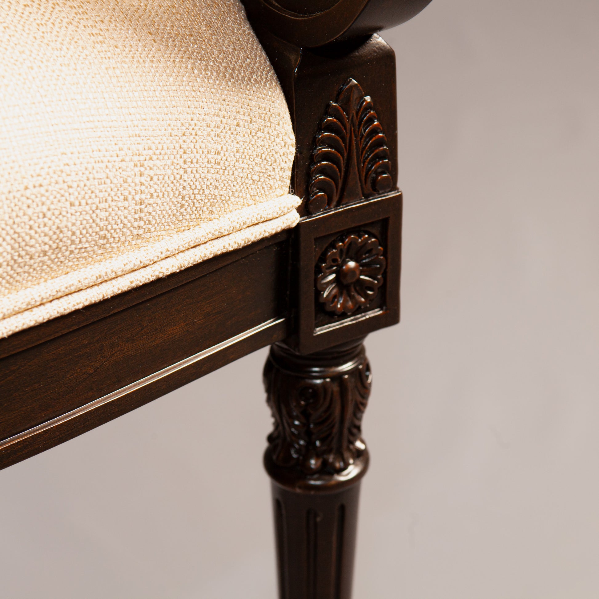 Empire-style armchair with elegantly curved armrests and detailed backrest carvings.