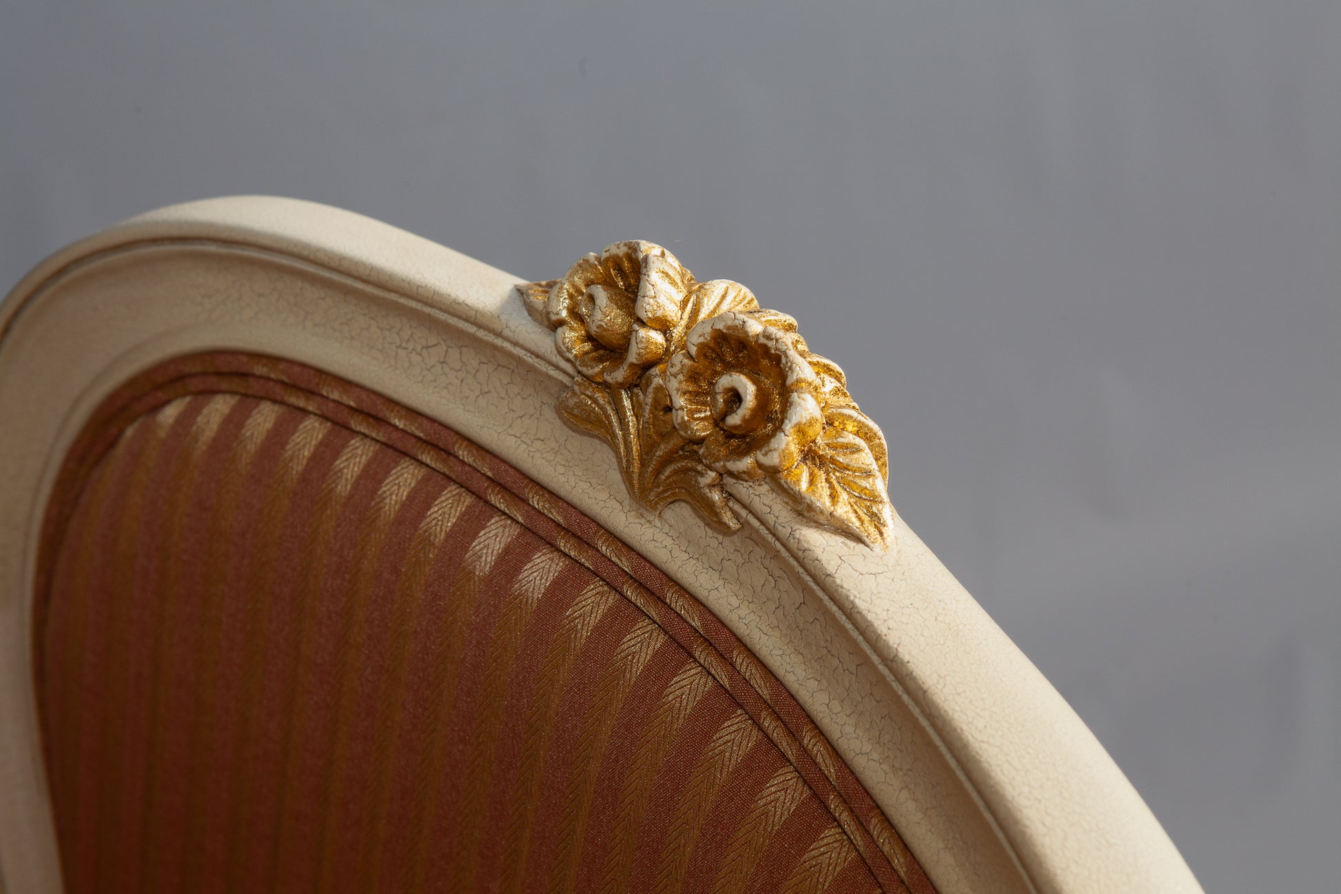 Side view of a Louis XV armchair highlighting detailed carvings and plush upholstery.