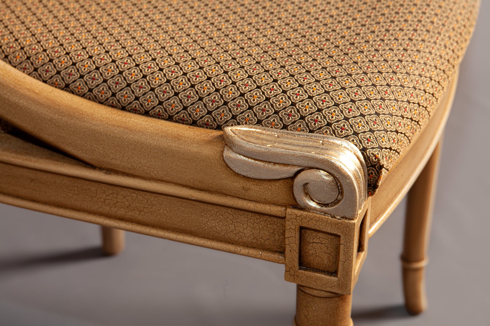 Close-up of chair's backrest highlighting ornate carvings and fabric pattern.