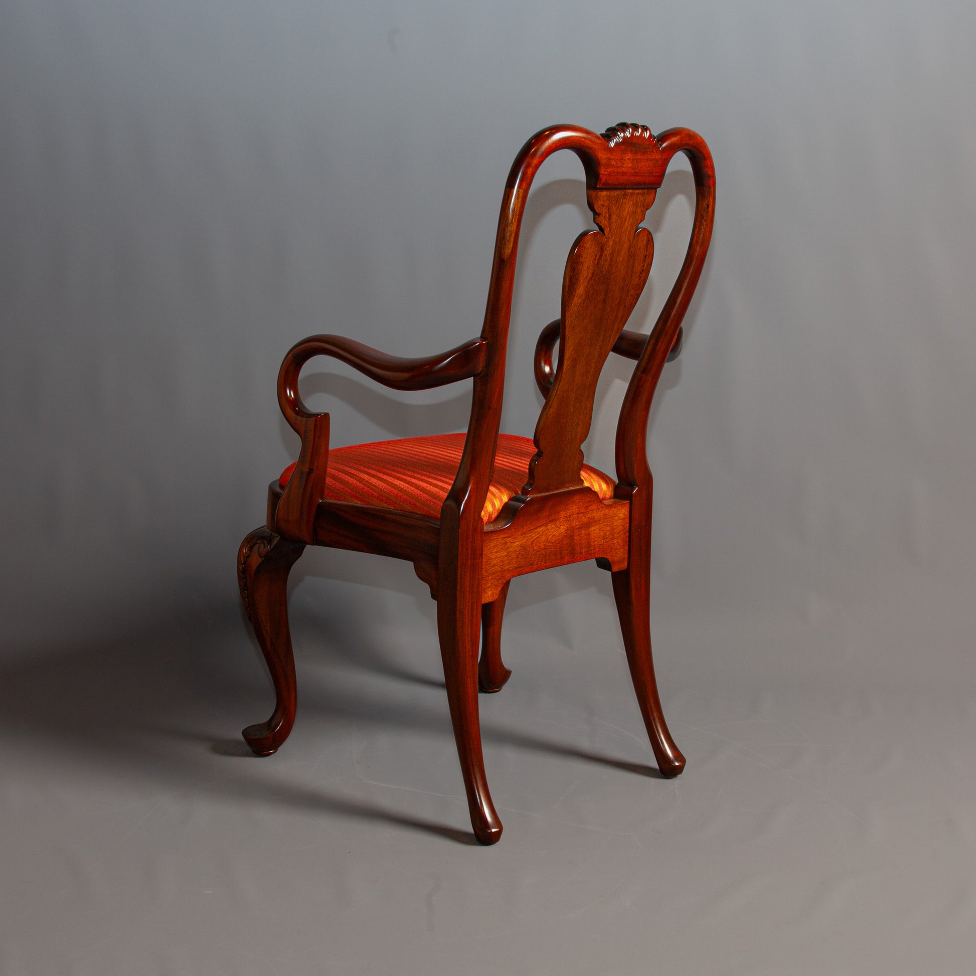 Elegant armchair with carved wooden frame and patterned fabric.