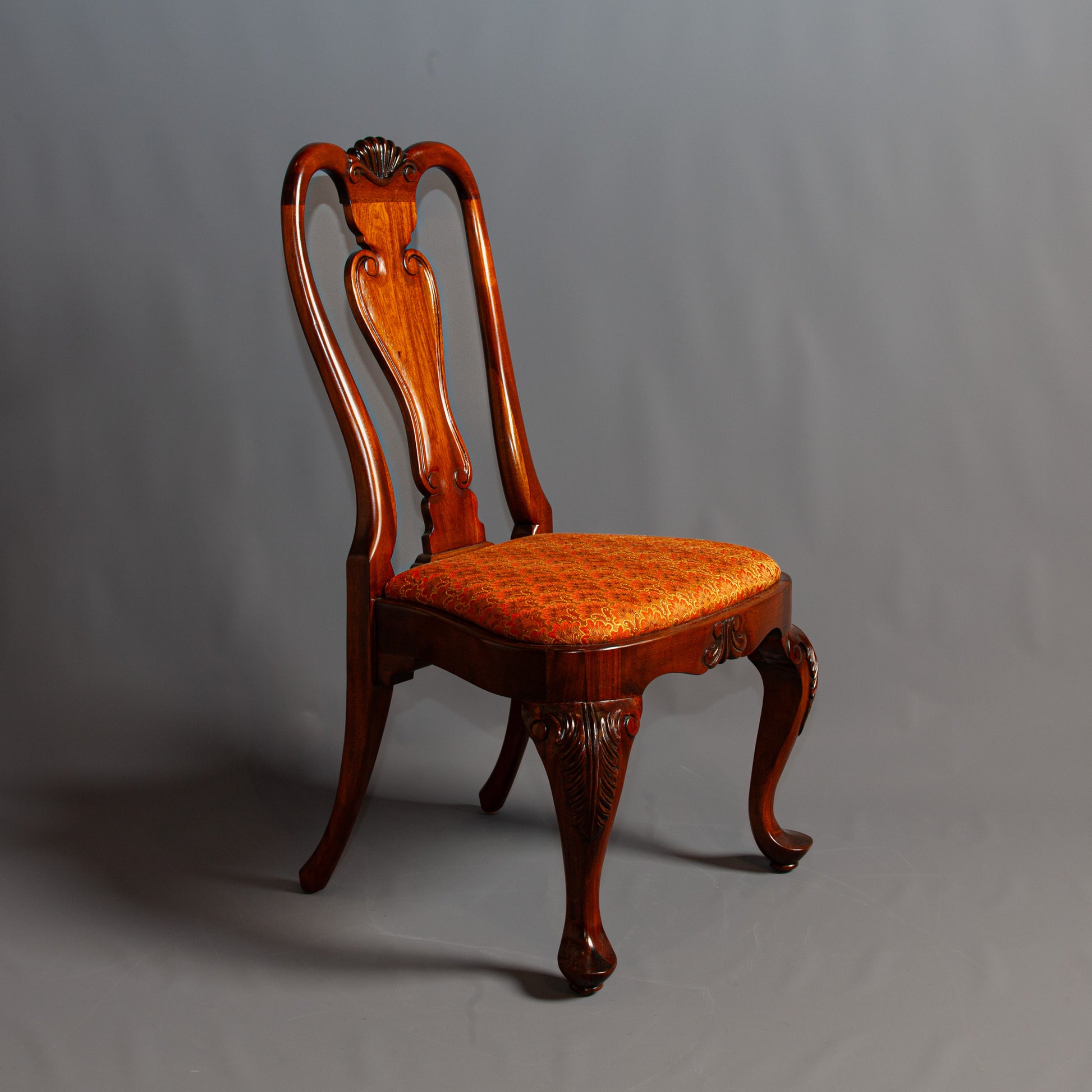 Front view of a refined side chair featuring a carved frame and cushioned seat.