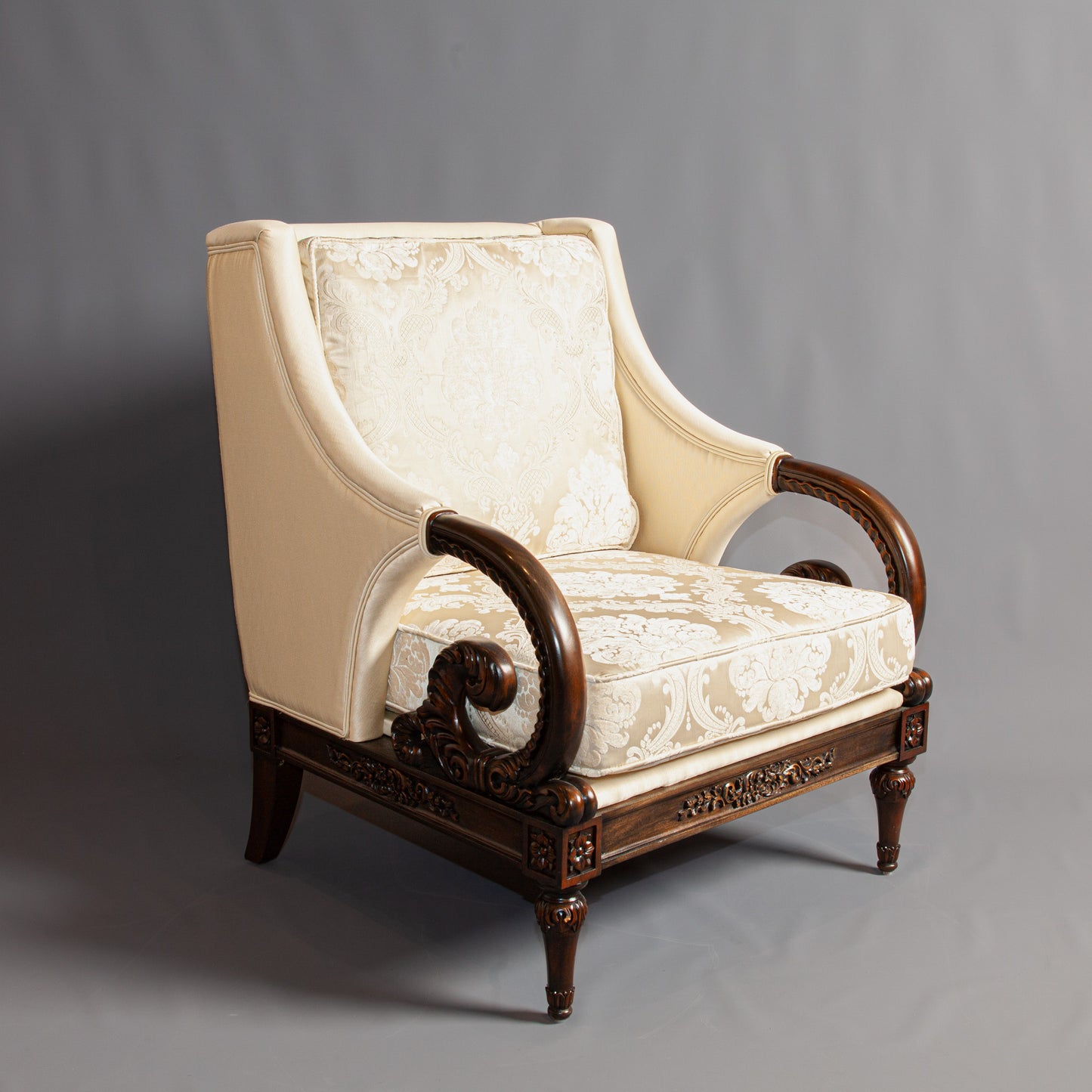 Full front view of an elegant armchair with intricate carvings and fabric seat.