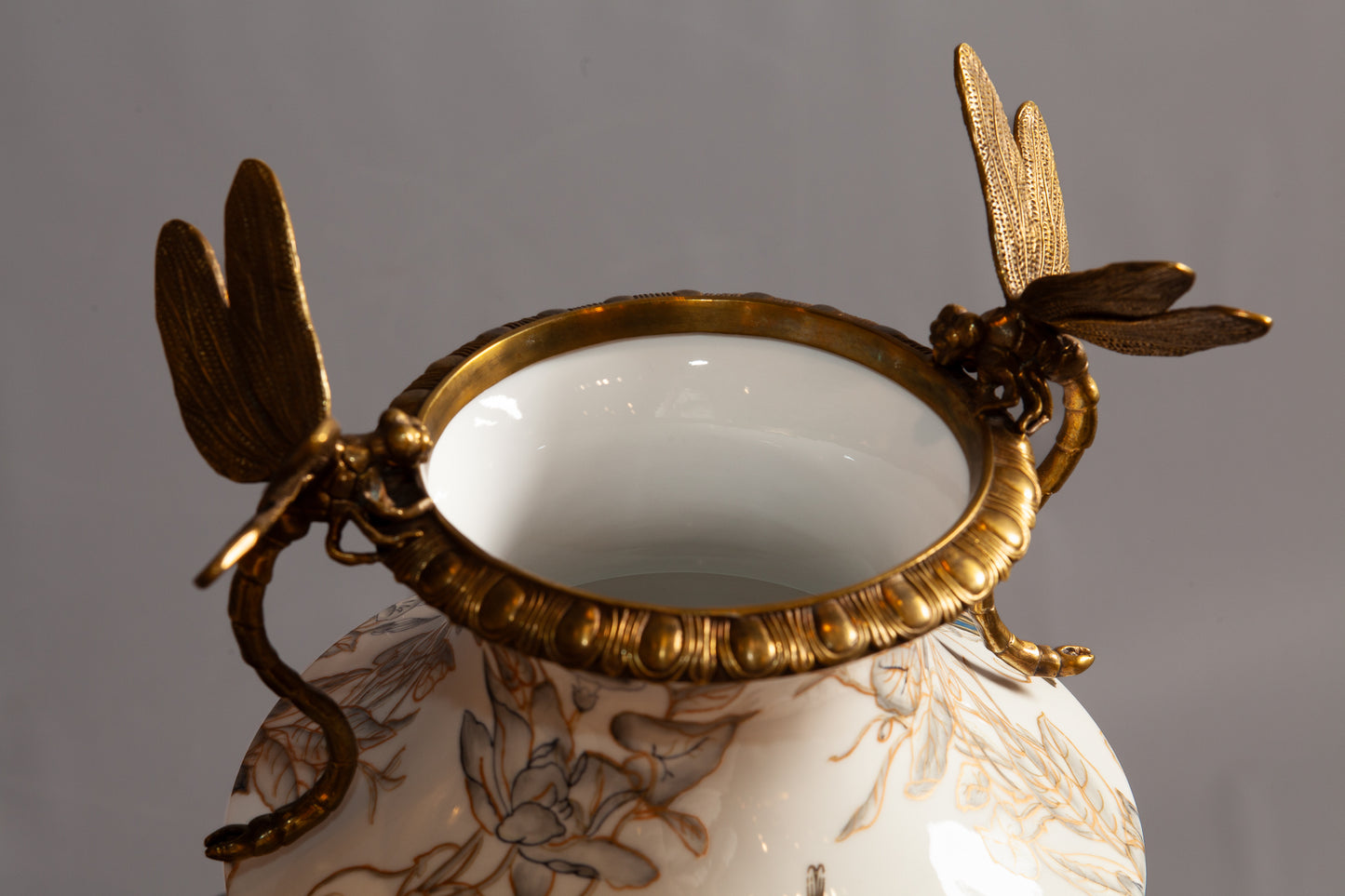 Close view of gold dragon fly on a painted porcelain vase with handles.