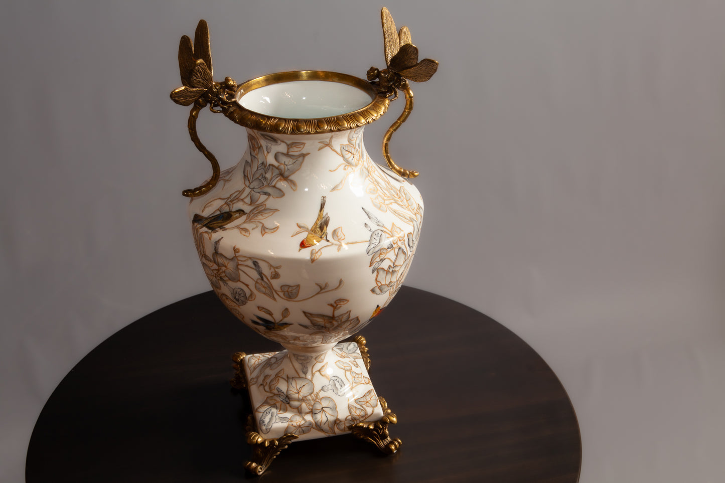 Side view of porcelain vase with gold butterfly handles and painted birds.