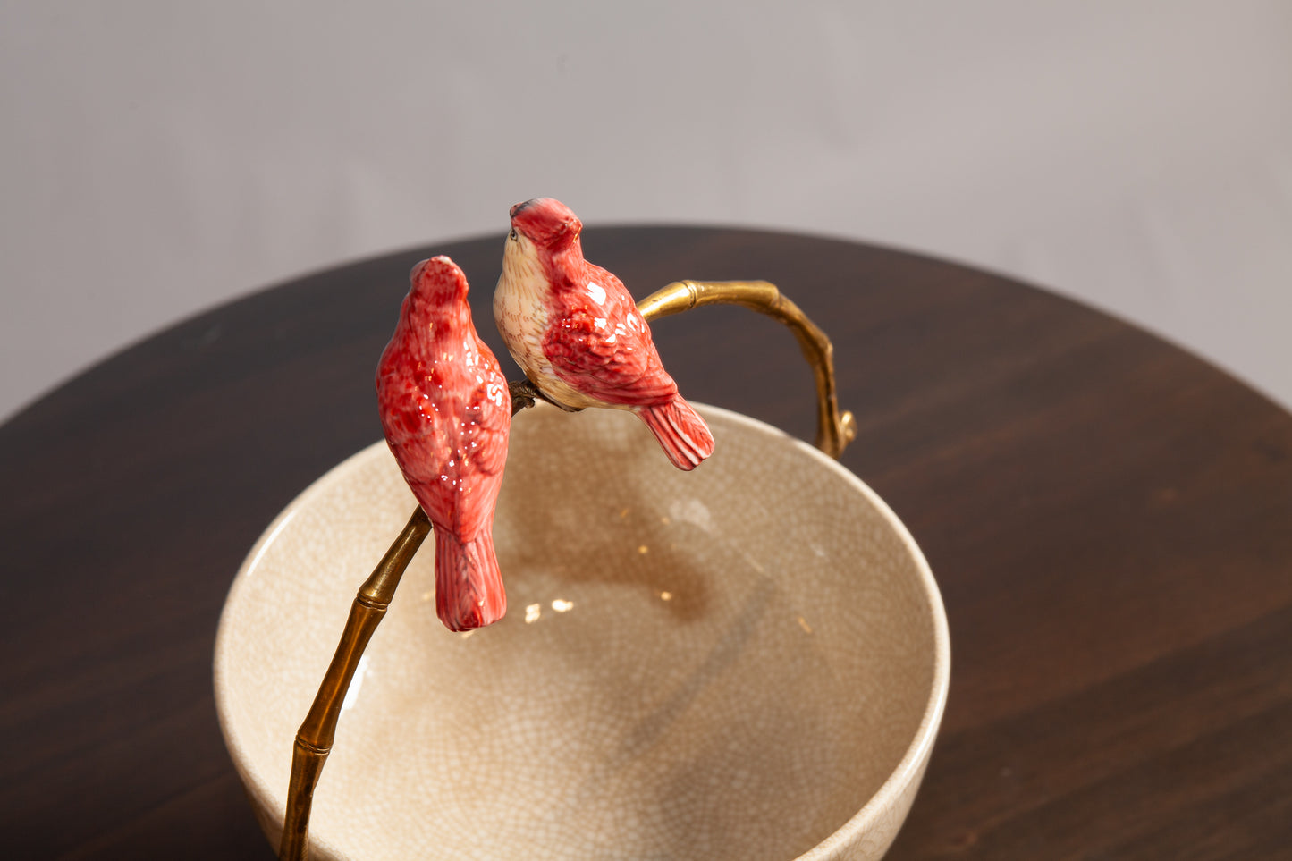 Back View of Two ceramic cardinals sit on a gold branch handle of a decorative bowl.