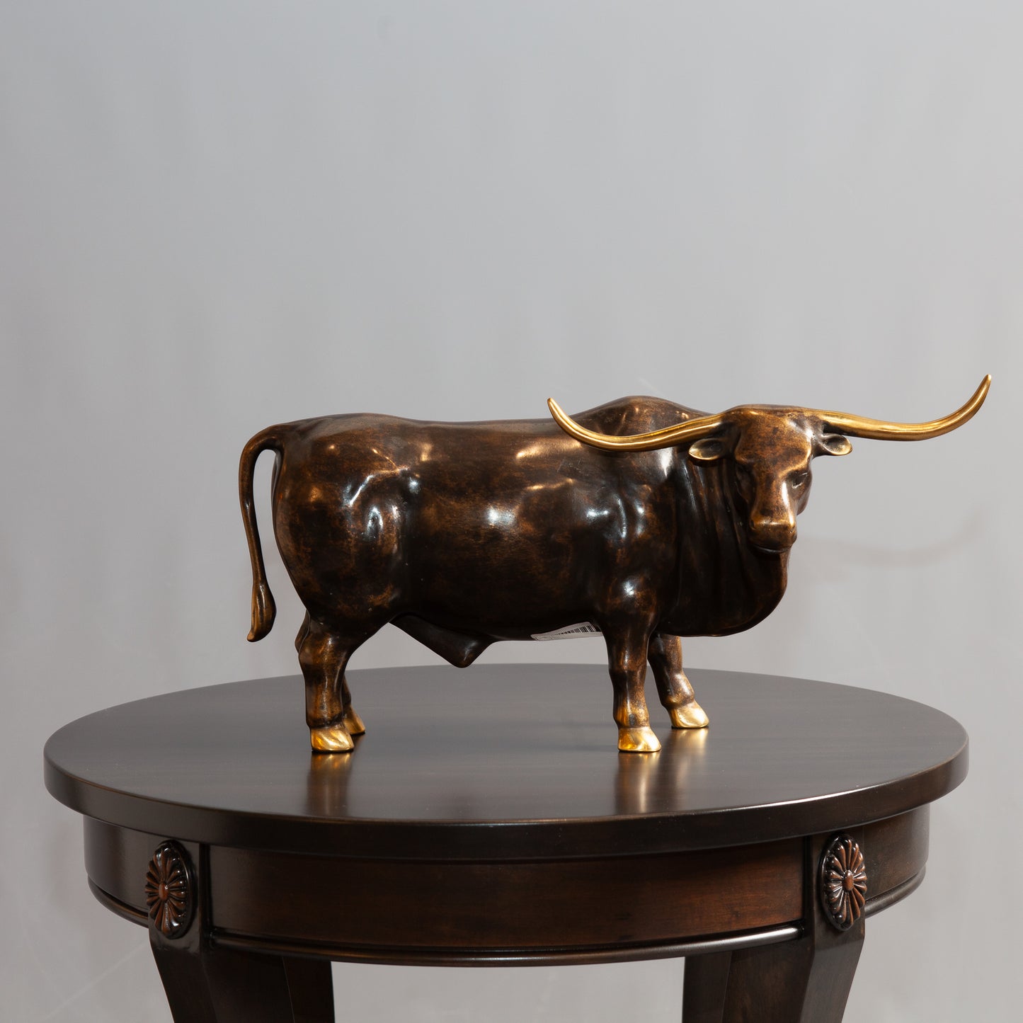 Bronze bull standing on a round brown table.