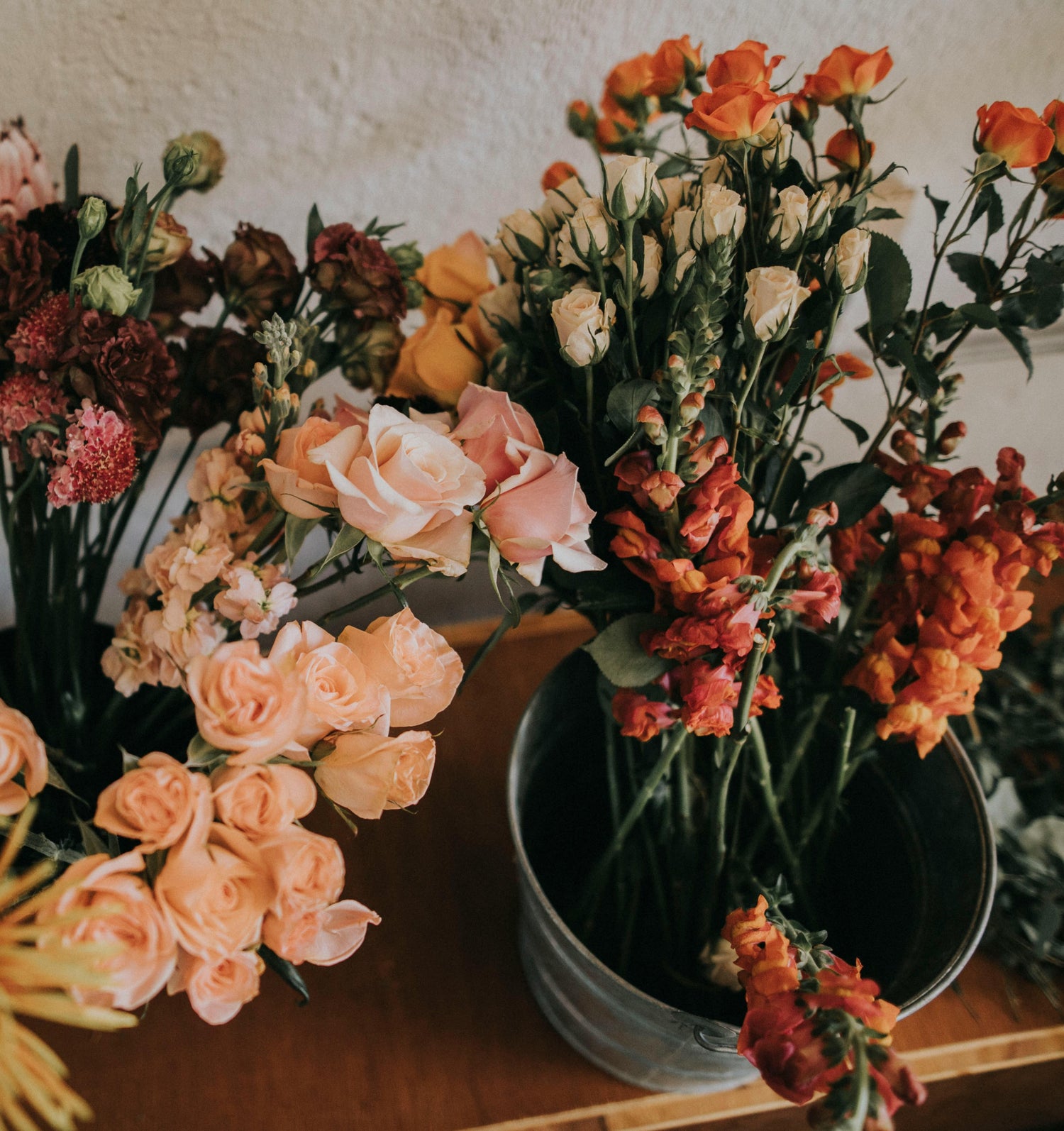 Vibrant indoor display of pink, yellow, red, and orange flowers in a rustic setting