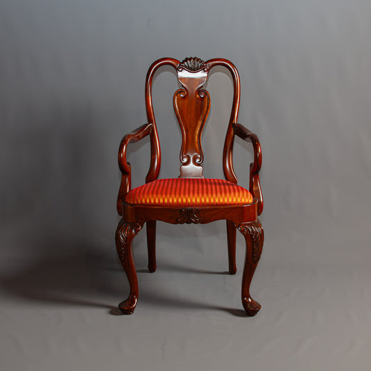 Classic armchair showcasing intricate woodwork and luxurious upholstery.