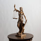 A bronze Lady Justice statue holding scales and a sword stands on a dark wooden table.